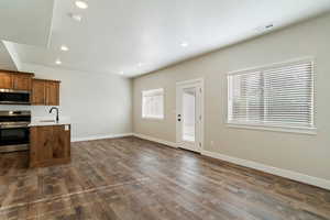 Kitchen featuring stainless steel appliances, dark wood-style flooring, recessed lighting, brown cabinetry, and a textured ceiling