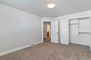 Unfurnished bedroom featuring light colored carpet, a closet, and a textured ceiling