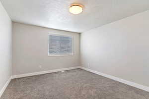 Unfurnished room featuring a textured ceiling and light carpet