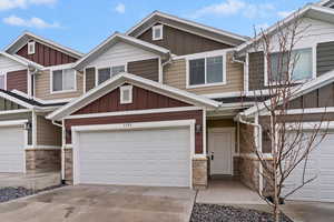 Craftsman-style home featuring stone siding, board and batten siding, and concrete driveway