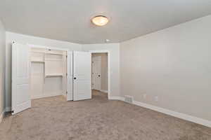 Unfurnished bedroom featuring a textured ceiling and light colored carpet