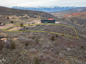 Aerial overview of property's location with property boundaries highlighted and a mountainous background