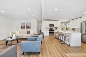 Living area featuring light wood-style flooring, vaulted ceiling, and recessed lighting