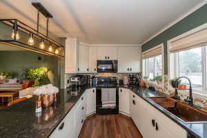 Kitchen featuring black appliances, dark stone counters, dark wood finished floors, pendant lighting, and tasteful backsplash