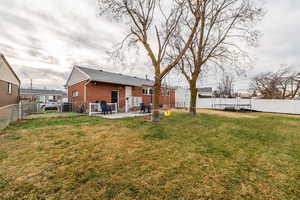 Back of property with a fenced backyard, a patio, brick siding, and a gate
