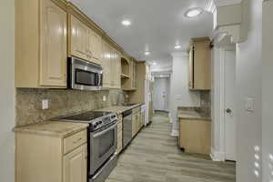 Kitchen featuring light brown cabinets, stainless steel appliances, decorative backsplash, and recessed lighting