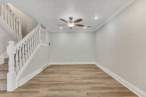 Empty room featuring stairway, recessed lighting, light wood finished floors, a ceiling fan, and crown molding