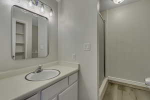 Hall bathroom featuring vanity, a shower stall, and light wood-style flooring