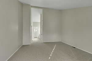 Primary bedroom featuring light carpet and vaulted ceilings