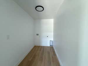 Laundry area featuring a textured ceiling, light wood finished floors, hookup for an electric dryer, and washer hookup