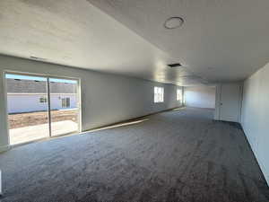 Carpeted empty room featuring a textured ceiling