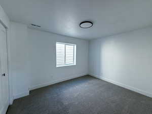 Spare room with dark carpet and a textured ceiling