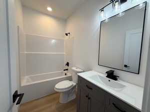 Bathroom with shower / tub combination, vanity, light wood finished floors, and recessed lighting