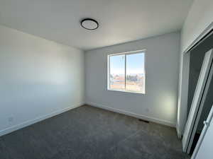 Empty room with dark colored carpet and baseboards