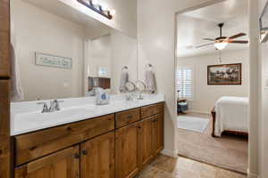 Bathroom with connected bathroom, double vanity, ceiling fan, light carpet, and light tile patterned floors