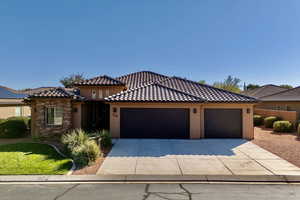 View of front facade featuring stucco siding, driveway, an attached garage, and a tiled roof