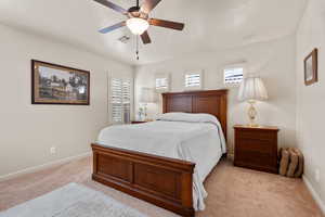 Bedroom with ceiling fan, light colored carpet, and a textured ceiling