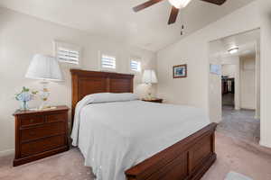 Bedroom featuring ceiling fan, lofted ceiling, light carpet, and a walk in closet