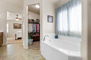 Full bathroom featuring a bath, vanity, a spacious closet, connected bathroom, and ceiling fan