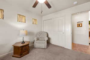 Living area with carpet floors and a ceiling fan