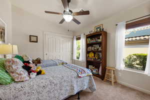 Bedroom with lofted ceiling, light carpet, a ceiling fan, and a closet