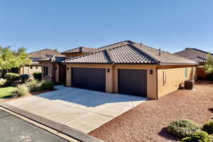 View of front of house with stucco siding, driveway, a garage, and a tiled roof