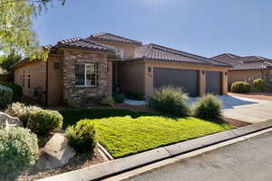 View of front of home featuring a front yard, concrete driveway, stucco siding, stone siding, and an attached garage
