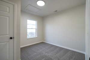 Carpeted empty room with attic access and baseboards