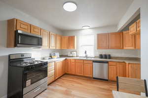 Kitchen featuring stainless steel appliances, light wood-style floors, light countertops, and light brown cabinetry