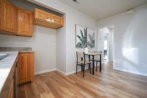 Kitchen featuring light wood finished floors, brown cabinetry, and light stone counters