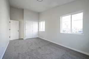Unfurnished bedroom featuring carpet floors, a closet, and a high ceiling