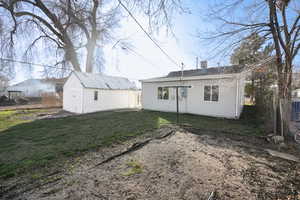 Rear view of house featuring a chimney and an outbuilding