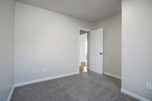 Empty room featuring carpet flooring and baseboards
