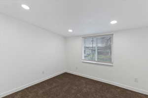 Spare room featuring dark colored carpet and recessed lighting