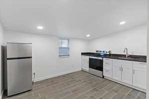 Kitchen with stainless steel appliances, dark stone counters, white cabinets, and recessed lighting