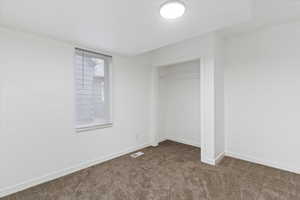 Unfurnished bedroom with dark carpet and a closet