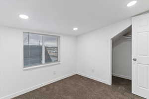 Empty room featuring dark colored carpet and recessed lighting