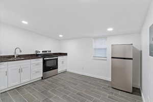 Kitchen featuring appliances with stainless steel finishes, dark stone countertops, white cabinets, recessed lighting, and electric panel