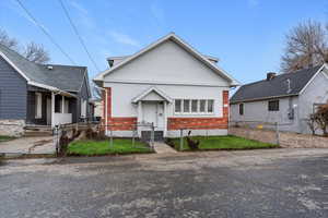 View of front of house featuring brick siding, a fenced front yard, and a gate