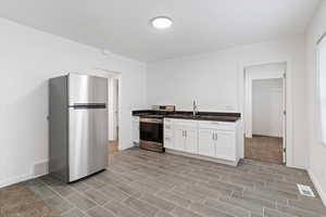 Kitchen with appliances with stainless steel finishes, white cabinetry, and dark stone countertops