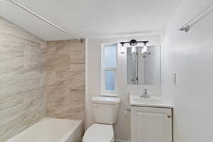 Full bath featuring vanity, bathing tub / shower combination, and a textured ceiling