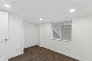 Unfurnished bedroom with a closet, dark carpet, and recessed lighting