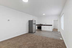 Kitchen featuring dark countertops, stainless steel appliances, white cabinets, and wood finish floors