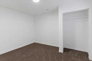 Unfurnished bedroom featuring dark carpet and a closet