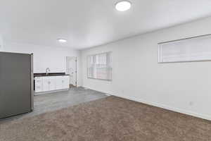 Interior space featuring dark countertops, freestanding refrigerator, white cabinetry, and wood tiled floors