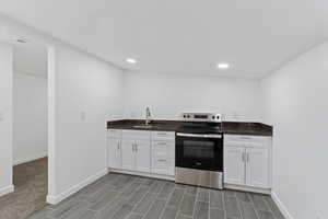 Kitchen with electric stove, white cabinetry, dark stone counters, wood finish floors, and recessed lighting
