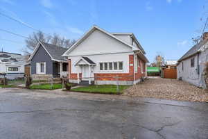 Bungalow with a fenced front yard, brick siding, and a gate