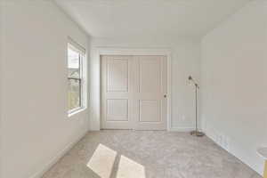 Unfurnished bedroom featuring light carpet and a closet