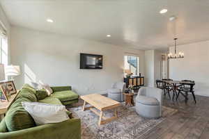 Living room featuring dark wood-style floors, recessed lighting, a textured ceiling, and a chandelier