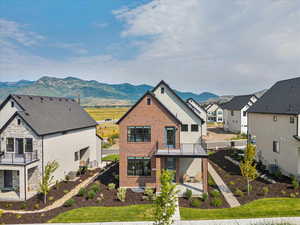 Back of property featuring a patio area, a mountain view, a residential view, a balcony, and brick siding